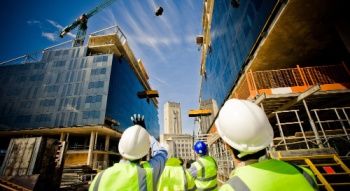 construction workers looking up at a crane